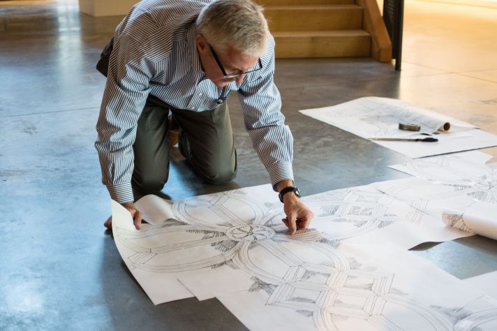 Roger Jackson laying out classical molding enrichments on floor.
